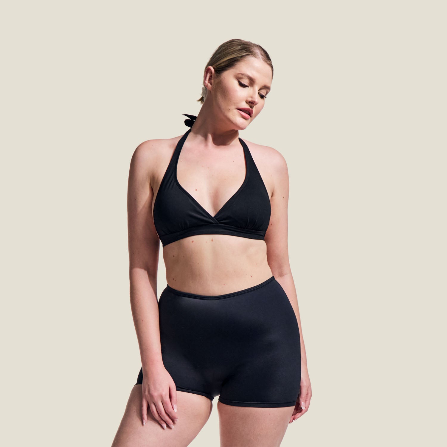 Model wearing WUKA Tie-Back Bikini Top in black, paired with swim shorts – front full-length product view.