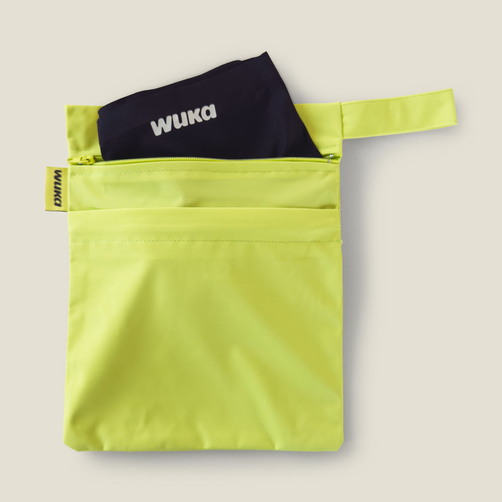 Lime punch WUKA two-pocket period changing bag holding a fresh pair of period pants, perfect for discreet storage of clean and used underwear on the go